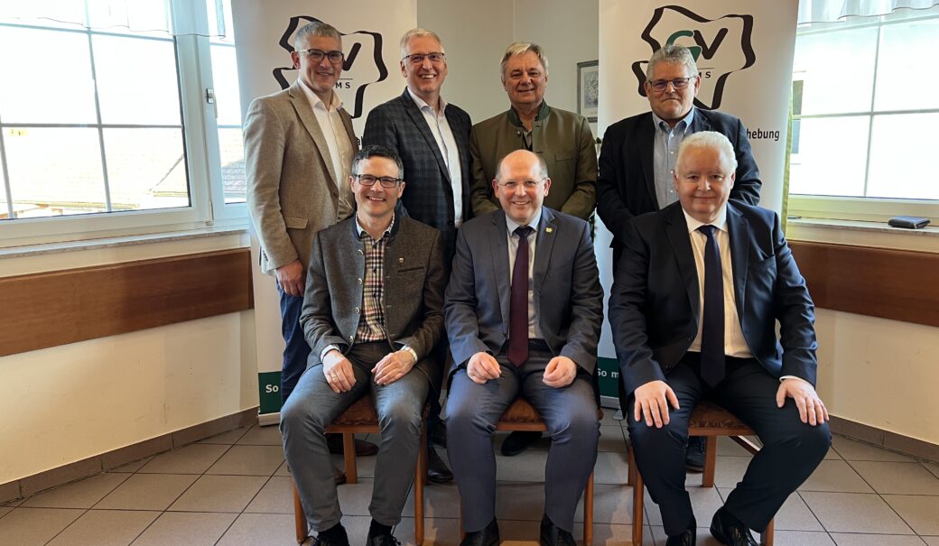 die genannten Personen sitzen bzw. stehen in einer Gruppe zusammen