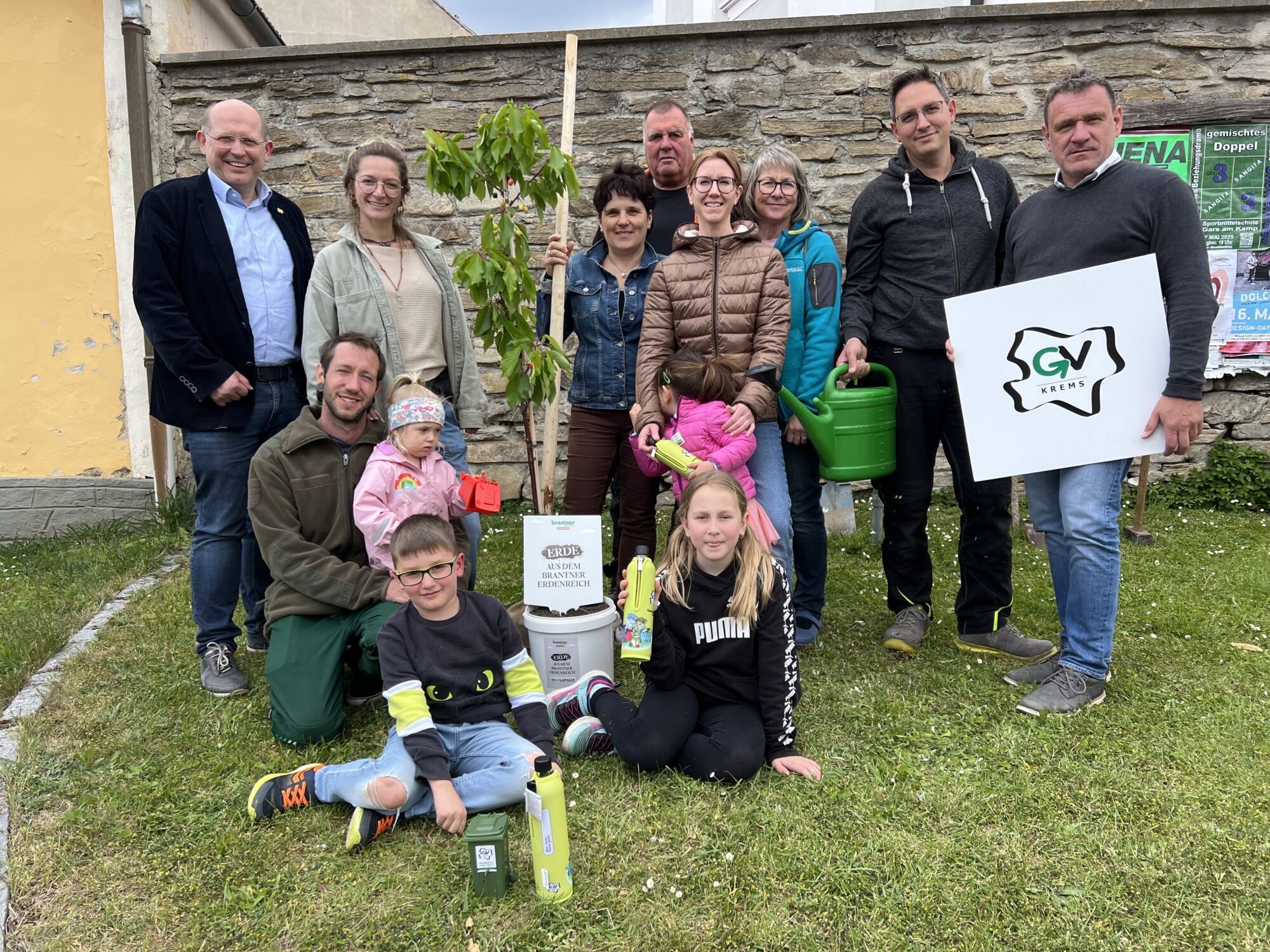 Die genannten Personen stehen rund um den Baum zusammen