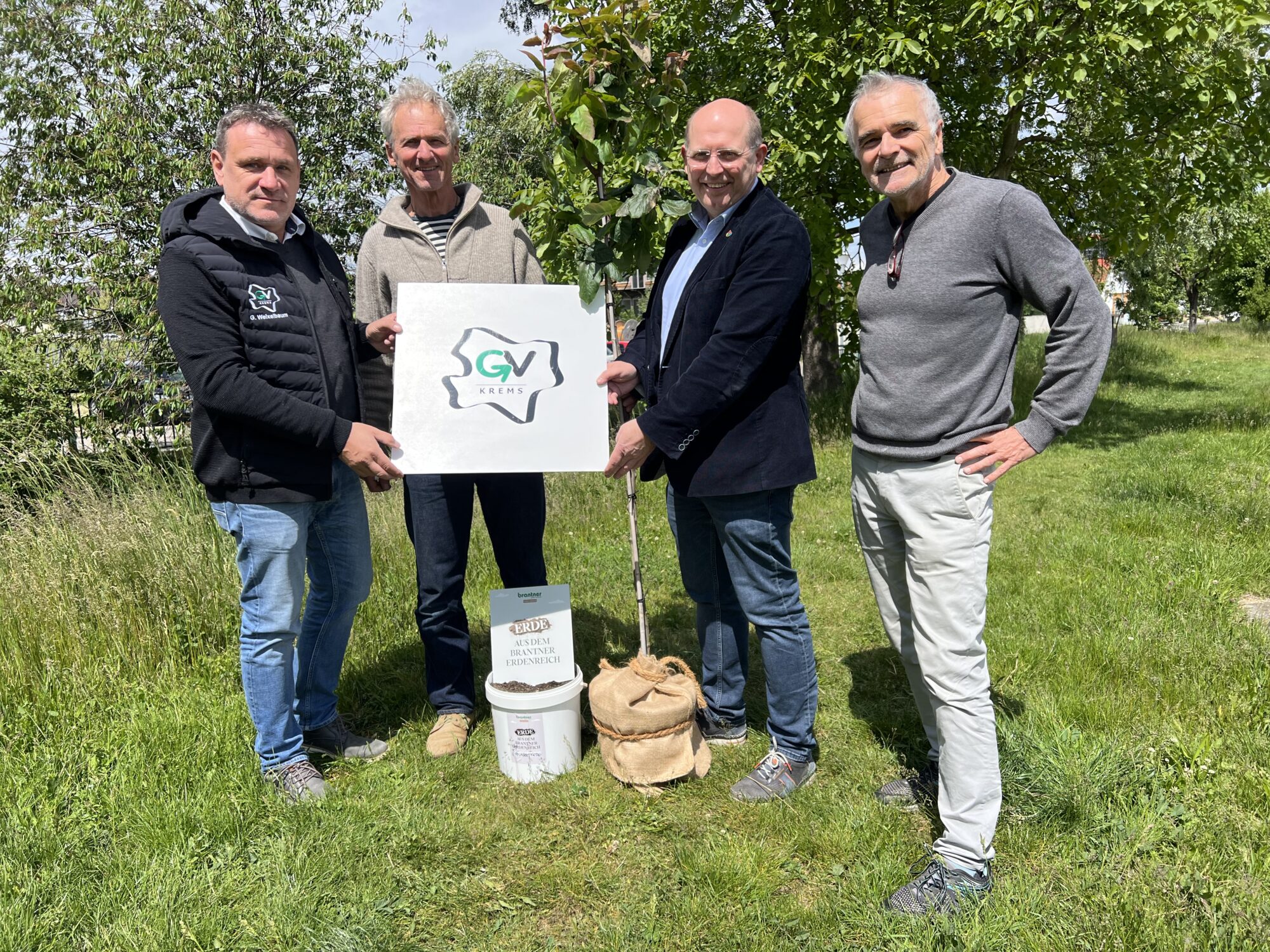 die genannten Personen stehen rund um den Baum zusammen
