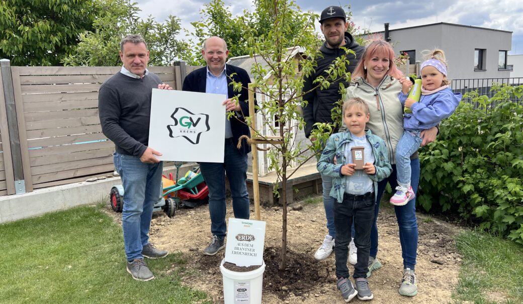 Die genannten Personen stehen im Garten vor dem Spielhaus der Kinder